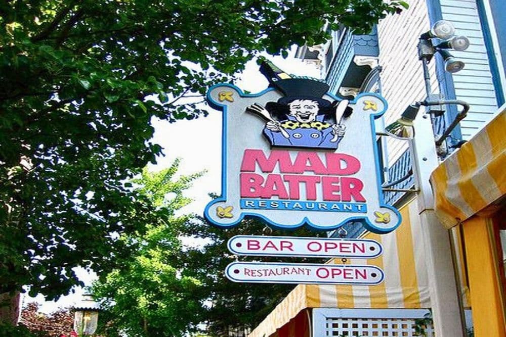 A colorful sign for the Mad Batter Restaurant, featuring a cartoonish chef and indicating that both the bar and restaurant are open.