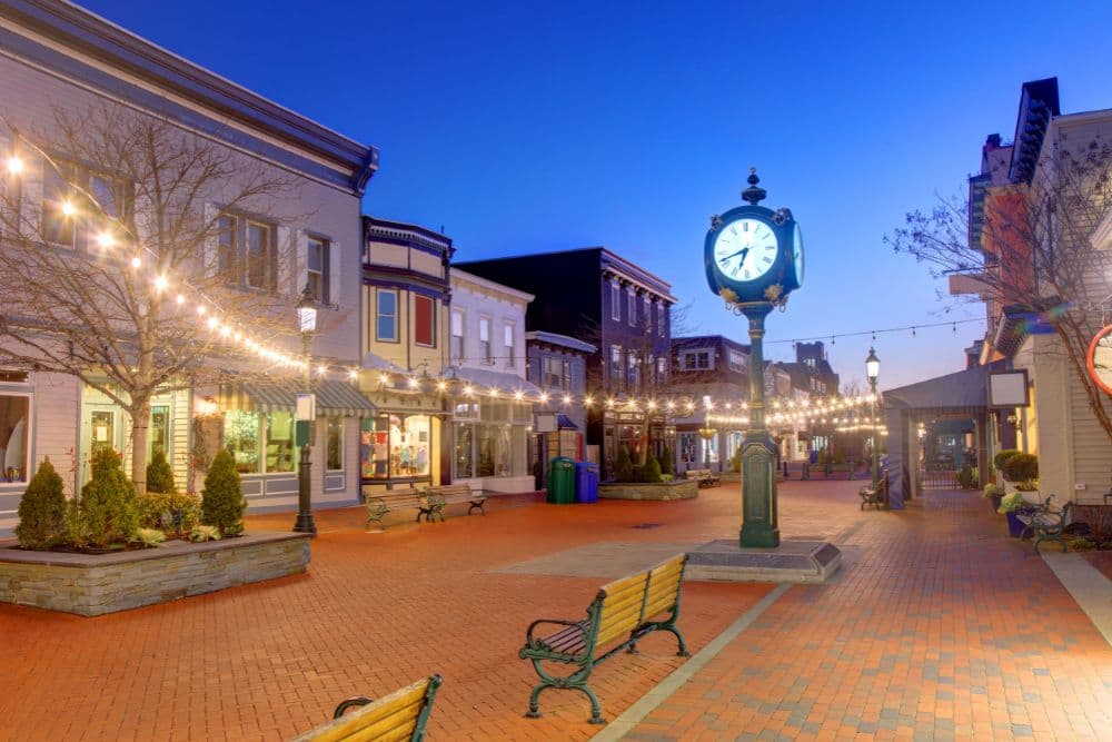 A charming town square at dusk featuring a clock and twinkling lights.